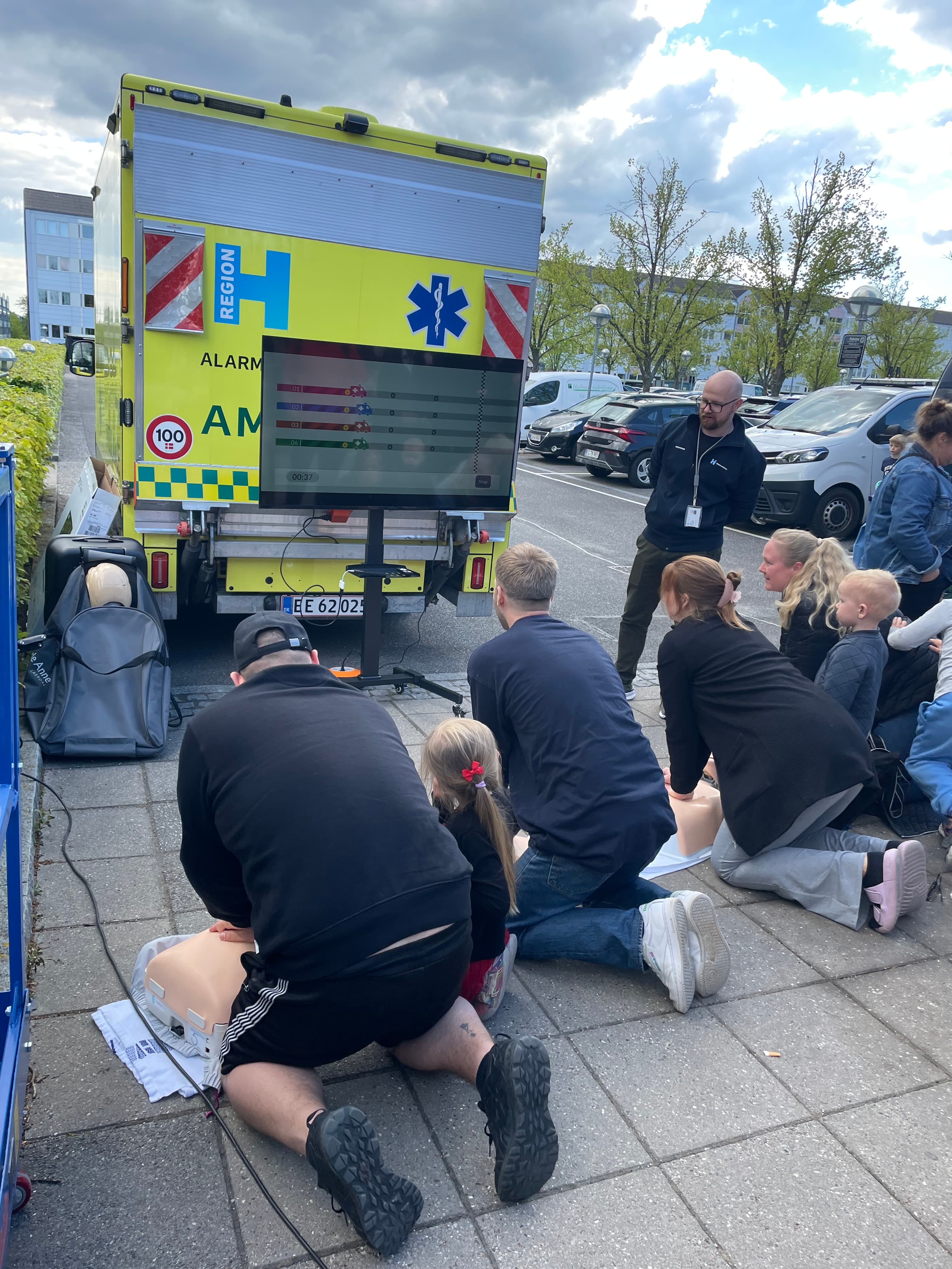 Deltagere træner hjertemassage ved en ambulance under et lokalt arrangement